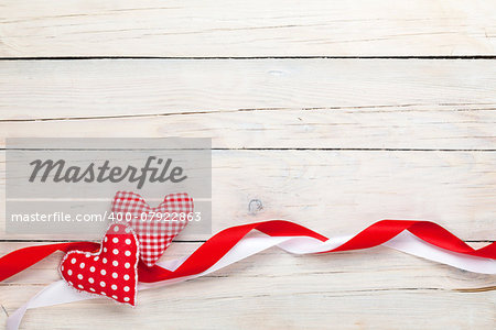 Valentines day background with toy hearts and ribbons over white wooden table background