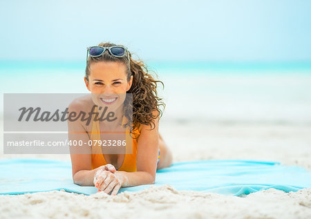 Smiling young woman laying on beach