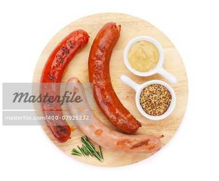 Various grilled sausages with condiments on cutting board. Isolated on white background