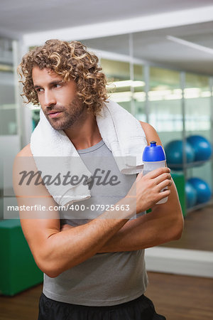 Handsome young man holding water bottle at the gym