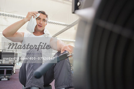 Fit man working out on rowing machine at the gym