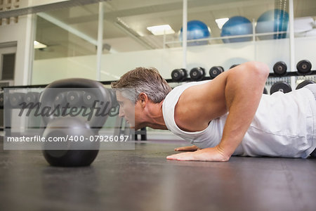 Fit man using kettlebells in his workout at the gym