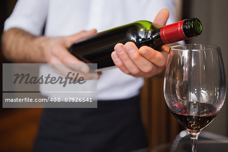 Waiter pouring a bottle of red wine in a bar