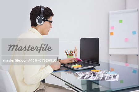 Businessman enjoying music and using laptop in his office