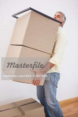 Man balancing heavy cardboard boxes at home in the living room