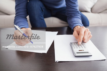 Young man paying his bills at home in the living room