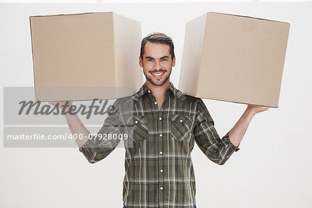Happy man holding moving boxes at home in the living room