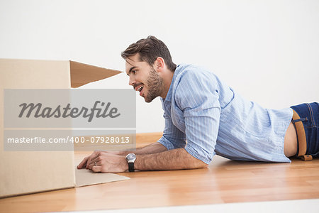Smiling man looking inside cardboard box at home in the living room
