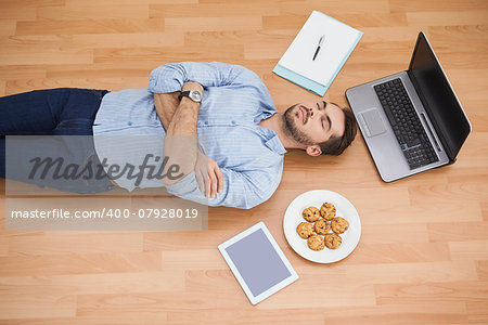 Casual man lying on floor surrounded by his possesions at home in the living room