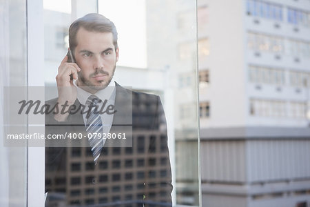Businessman looking out window on the phone in his office