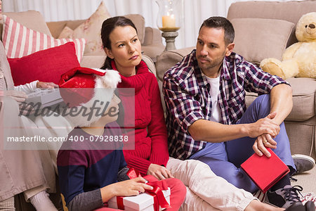 Thinking family sitting and holding gifts at home in the living room