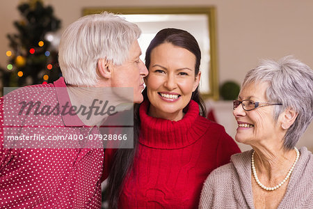 Grandfather kissing the mother at christmas at home in the living room