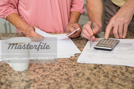 Senior couple paying their bills at home in the kitchen