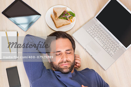 Sleeping man lying on floor surrounded by his things at home in the living room