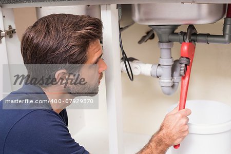 Plumber fixing under the sink in the kitchen