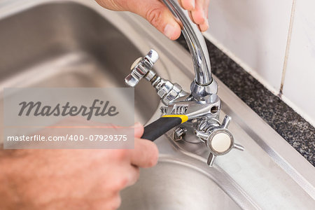 Plumber fixing the sink with wrench in the kitchen
