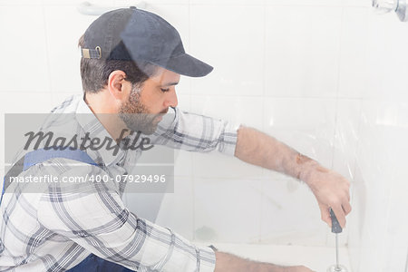 Handyman fixing toilet with screwdriver in the bathroom