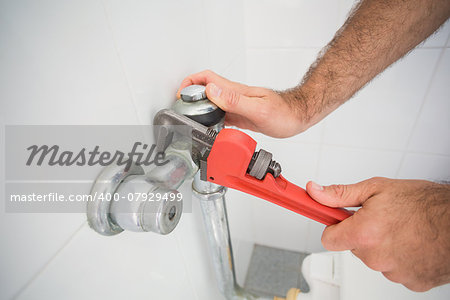 Plumber fixing tap with wrench in the bathroom