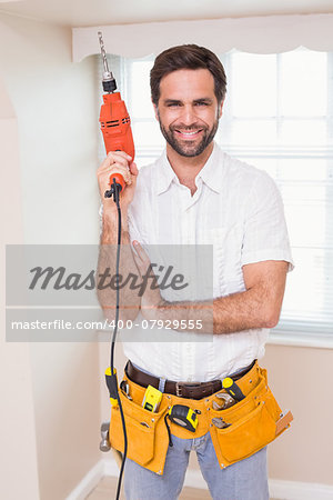 Handyman smiling at camera holding drill in a new house
