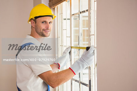 Construction worker using measuring tape in a new house