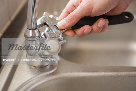 Man fixing tap with pliers at home in the kitchen