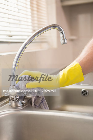 Hand cleaning a sink with cloth at home in the kitchen