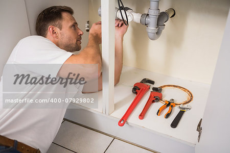 Plumber fixing under the sink in the kitchen