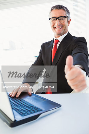 Positive businessman in suit with thumbs up in his office