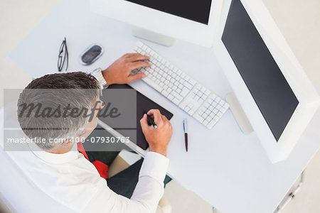 Businessman using digital tablet and computer in his office