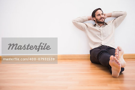 Thoughtful man leaning against wall with crossed arms in the living room