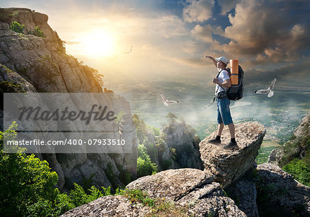 Tourist on the top of a rock at sunrise