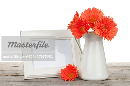 Orange gerbera flowers and photo frame on wooden table on white background