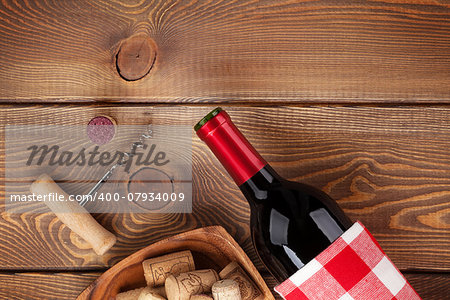 Red wine bottle, bowl with corks and corkscrew. View from above over rustic wooden table background