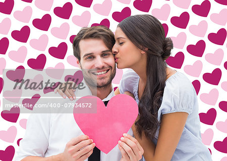 Pretty brunette giving boyfriend a kiss and her heart against valentines day pattern