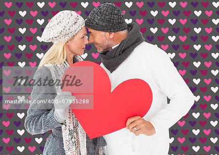 Smiling couple in winter fashion posing with heart shape against valentines day pattern