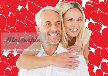 Happy man giving his partner a piggy back against valentines day pattern