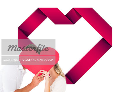 Attractive young couple kissing behind large heart against heart