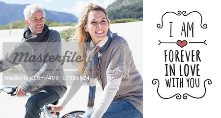 Carefree couple going on a bike ride on the beach  against valentines message