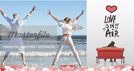 Couple jumping on the beach together against love is in the air