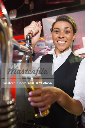 Pretty barmaid pulling pint of beer in a bar