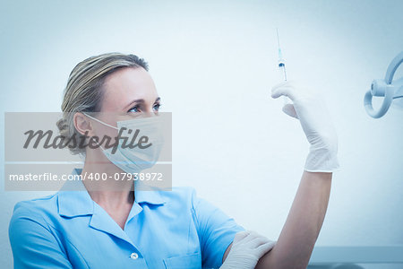 Concentrated female dentist in surgical mask holding injection