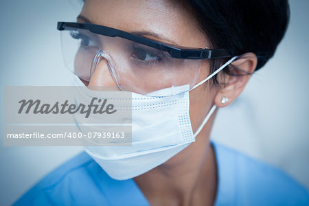 Close up of female dentist wearing surgical mask and safety glasses