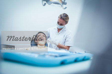 Female dentist examining womans teeth in the dentists chair