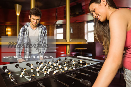 Smiling friends playing table football in a pub