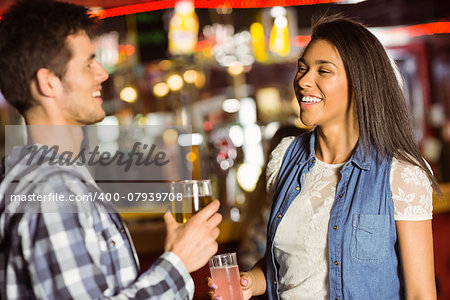 Smiling friends drinking beer and mixed drink in a bar