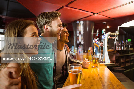 Smiling brown hair standing with arm around his friends