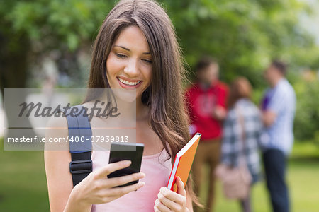 Happy student sending a text outside on campus at the university