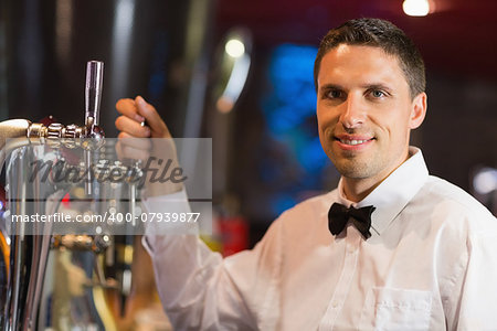 Handsome barman smiling at camera in a bar