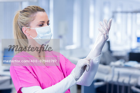 Dental in mask pulling on gloves at the dental clinic
