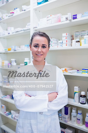 Portrait of a smiling student in lab coat with arms crossed in the pharmacy